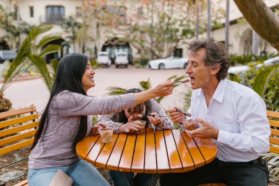 Smiling family enjoying quality time eating ice cream at an outdoor table.