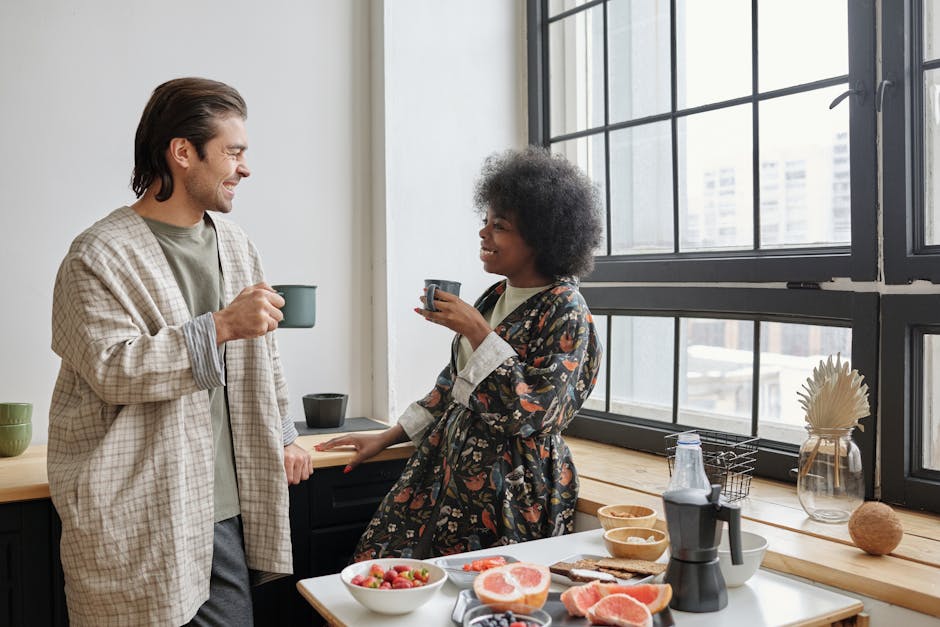 A happy couple enjoys morning coffee in a bright kitchen, sharing smiles and conversation.