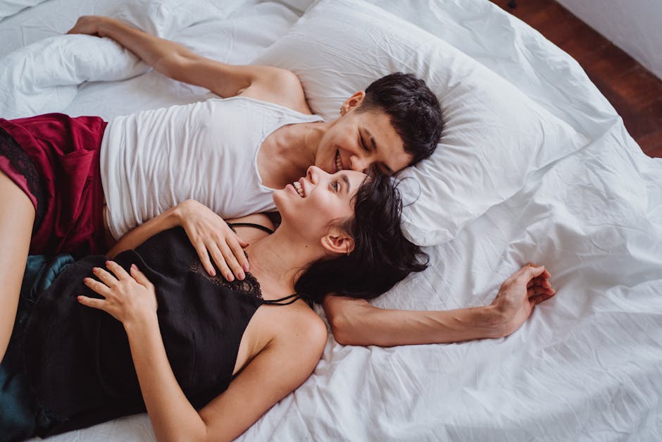 A joyful couple relaxing in bed, sharing intimate and happy moments together.