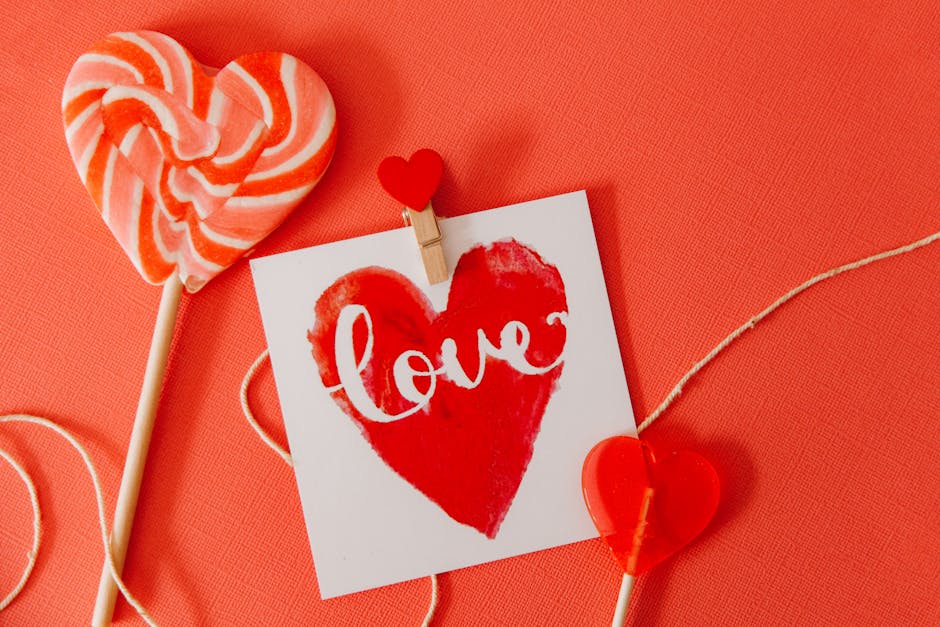 Heart-shaped lollipops and a 'love' card on a red background, perfect for Valentine's Day.