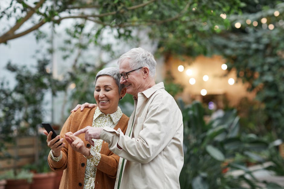 Happy senior couple using smartphone together in lush garden setting, embracing technology and leisure.