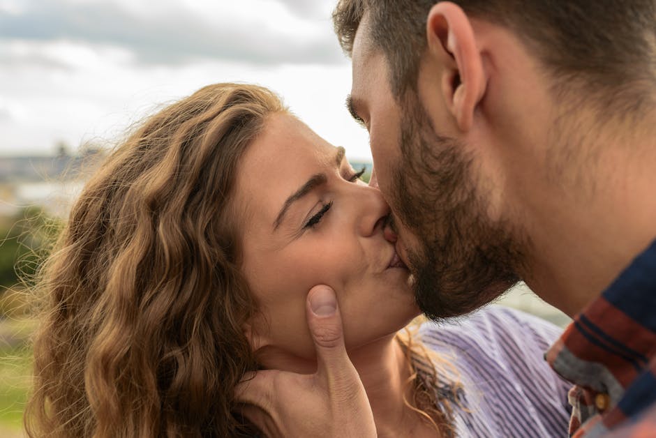 Close-up of a couple sharing a passionate kiss outdoors, capturing a moment of romance and affection.