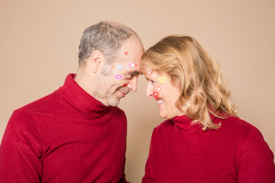 Joyful elderly couple wearing red sweaters with stickers, celebrating love.