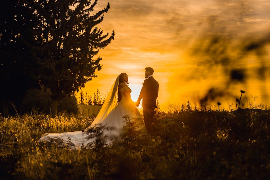 Bride and groom holding hands during a stunning golden sunset outdoors.