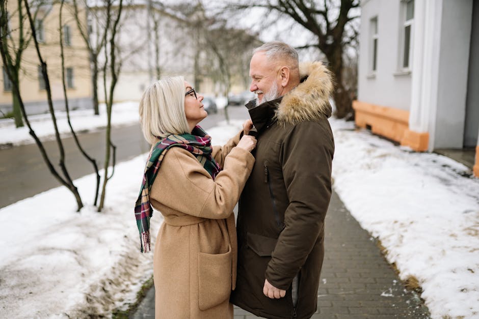 Happy senior couple enjoying a winter day outdoors, smiling face to face in warm clothes.