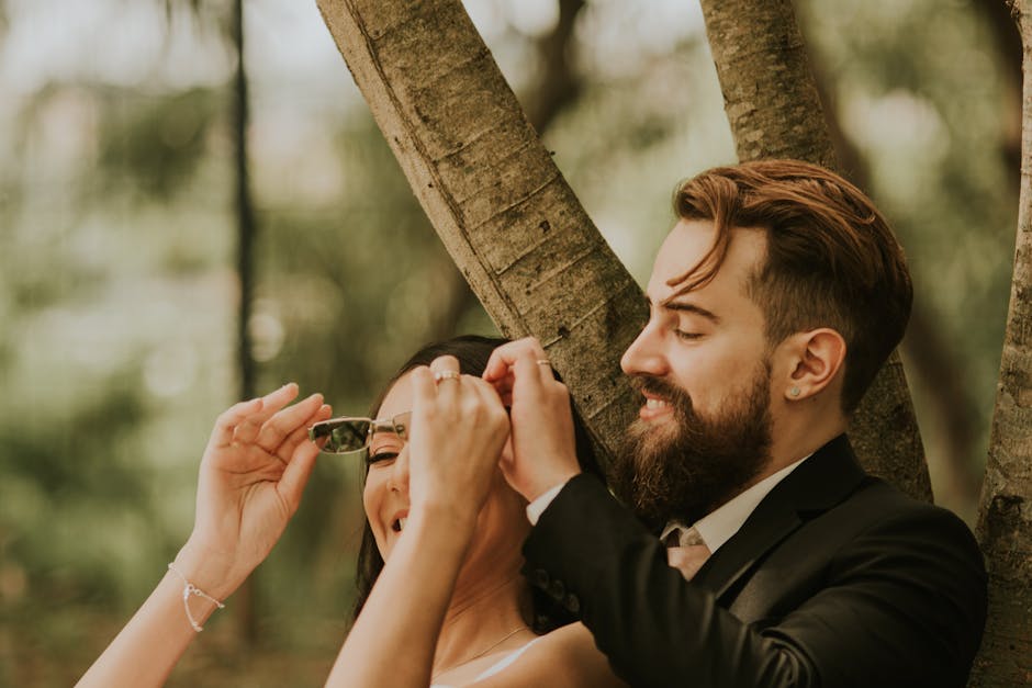 Happy young newlywed couple laughing together beneath a tree outdoors.