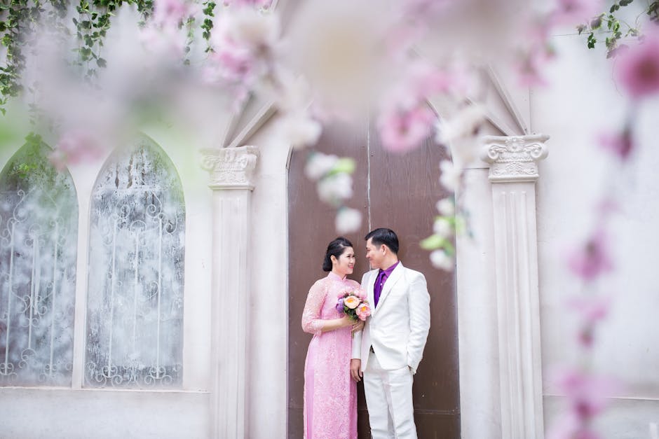 Bride and groom in a floral archway, sharing a romantic moment on their wedding day.