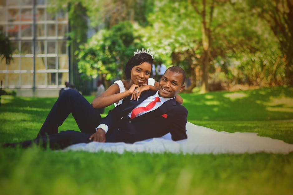 African couple in wedding attire posing on grass in lush outdoor setting in Zambia.