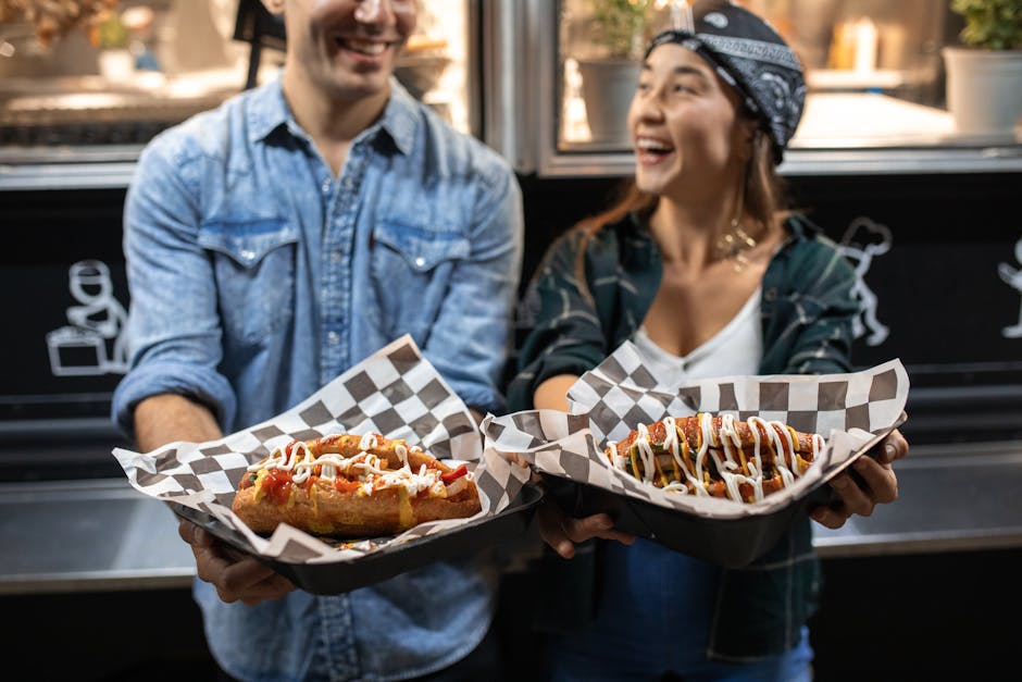 Laughing couple holding gourmet street food outside a food truck at night.
