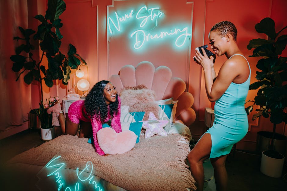 Two women enjoying a lively indoor photo session with vibrant decor and neon lights.