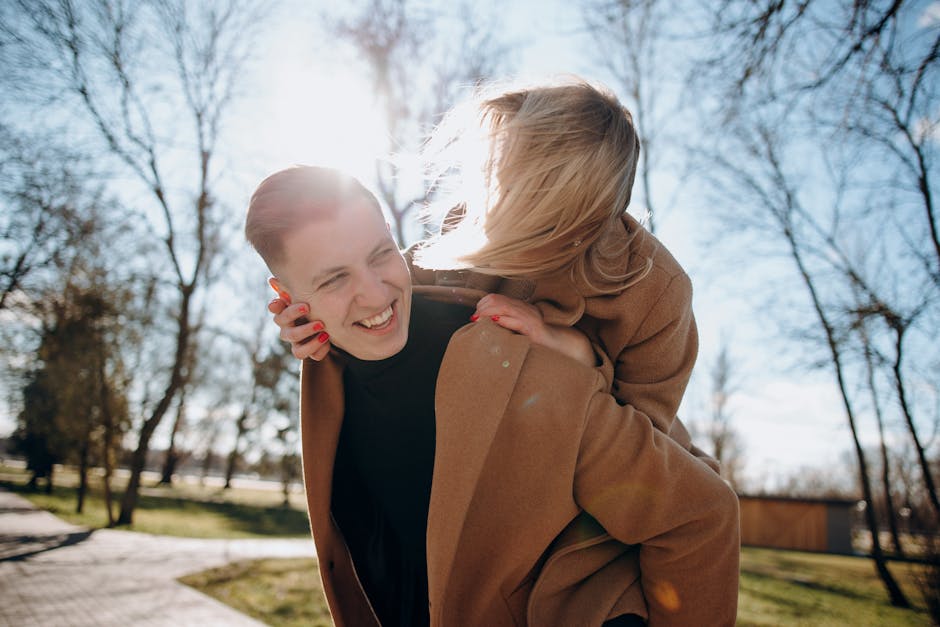 Smiling couple enjoying a playful moment outdoors on a sunny day, showcasing love and warmth.