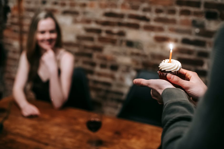 A joyful indoor moment with a celebratory cupcake and candle shared between a couple.