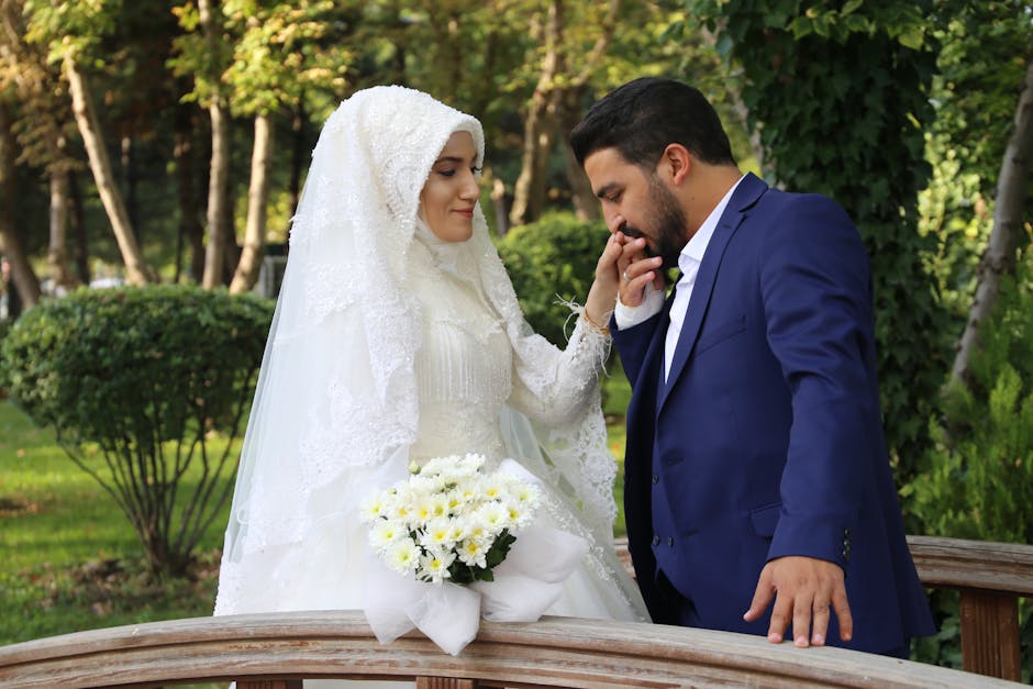 A bride and groom share a tender moment in a picturesque outdoor setting with lush greenery.