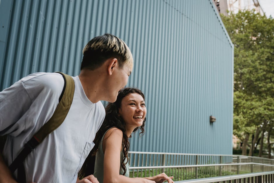 Cheerful couple laughing and enjoying a moment together outdoors near a large building.