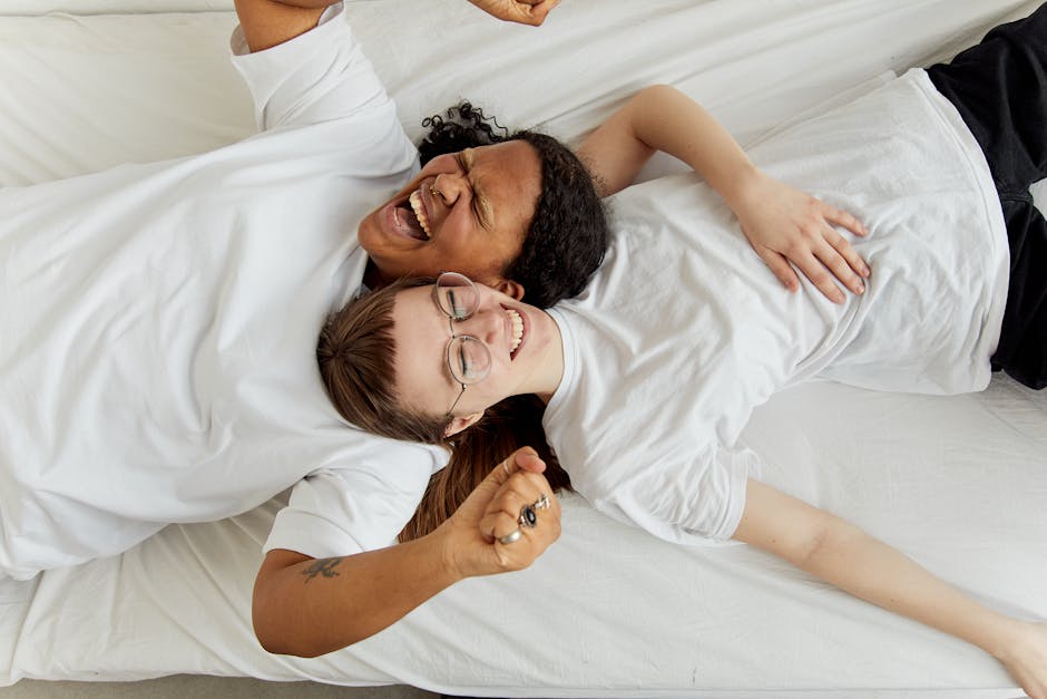Happy couple lying on bed embracing and laughing, capturing a moment of joy and connection.
