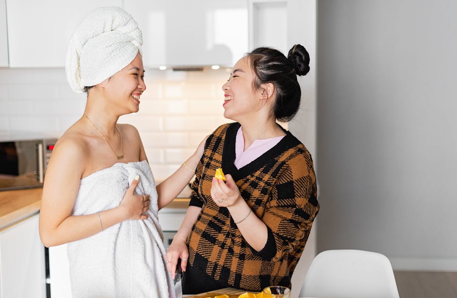 Two women laughing together in a modern kitchen, sharing a joyful moment.
