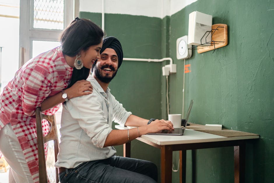 Cheerful couple using a laptop in a cozy home setting, smiling and enjoying their time.