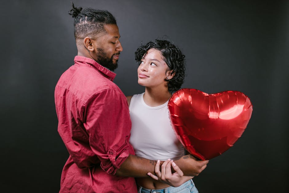 A loving couple embracing with a red heart balloon, perfect for Valentine's Day themes.