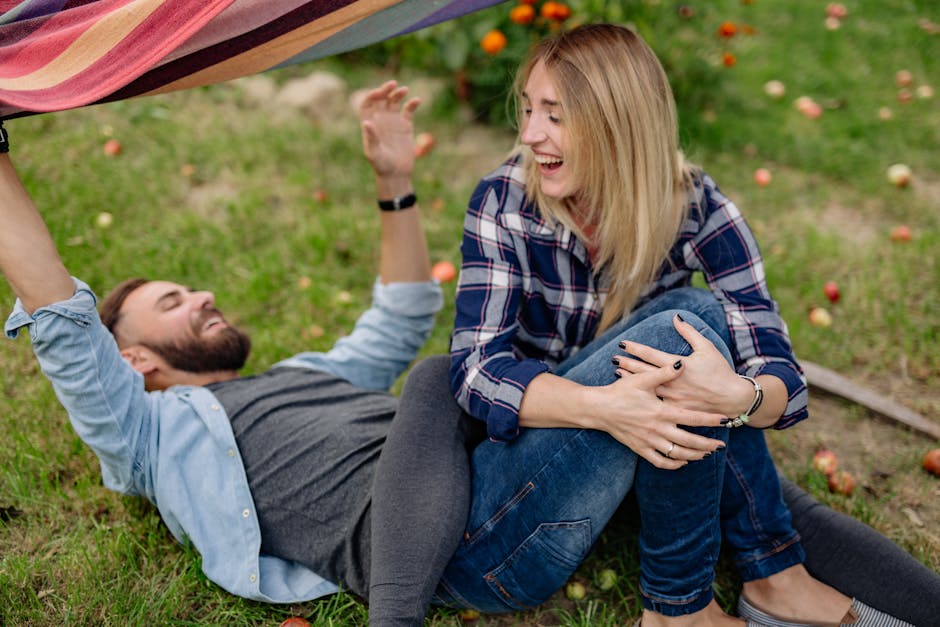 A joyful couple enjoying a playful moment outdoors on the grass, surrounded by apples.