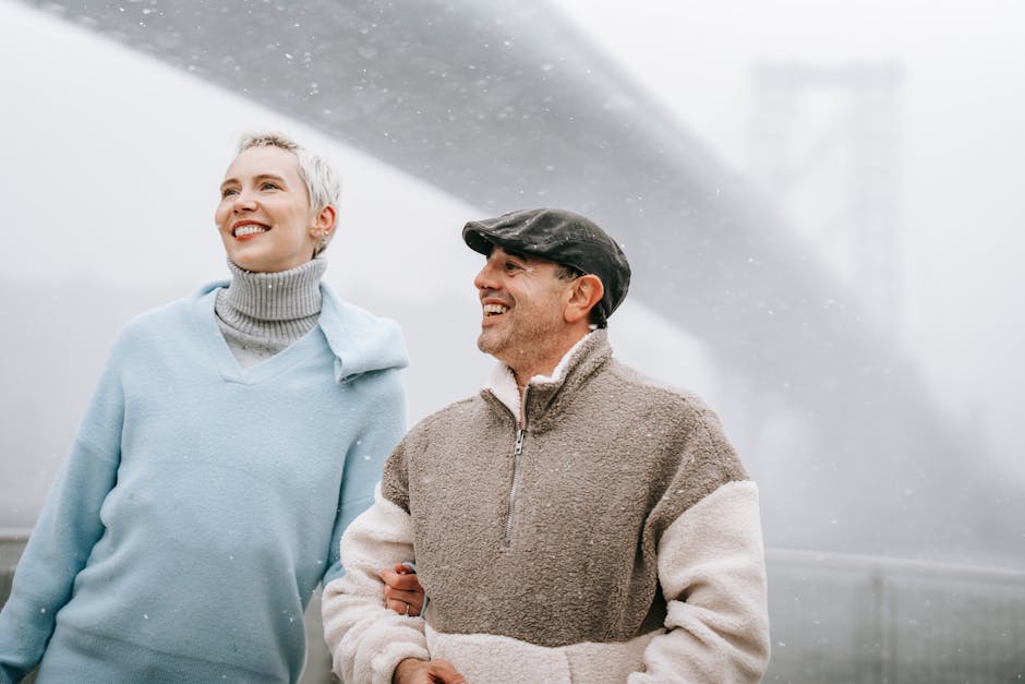 Happy couple enjoying a foggy day outdoors near a bridge.