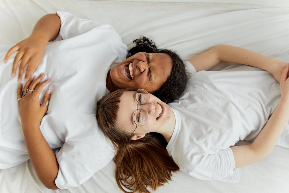 Happy couple lying together laughing, showcasing love and affection in an intimate moment.