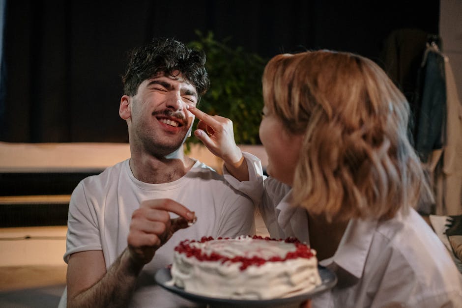 A couple enjoys a fun indoor celebration with a decorated cake and laughter.