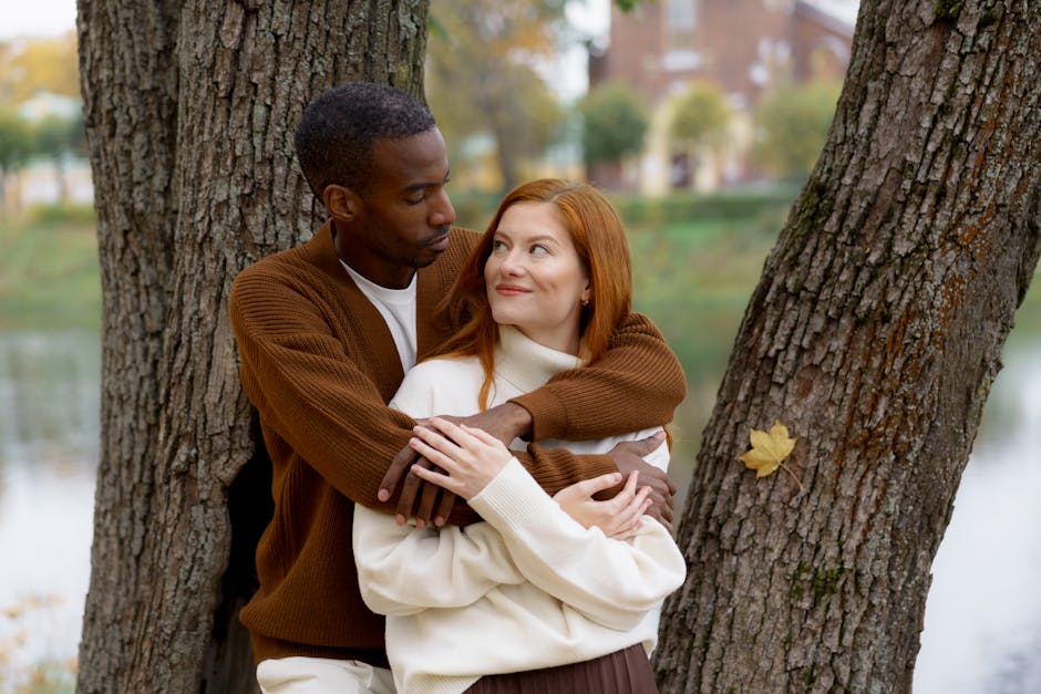 A loving couple embraces outdoors in a beautiful autumn setting by the lake.