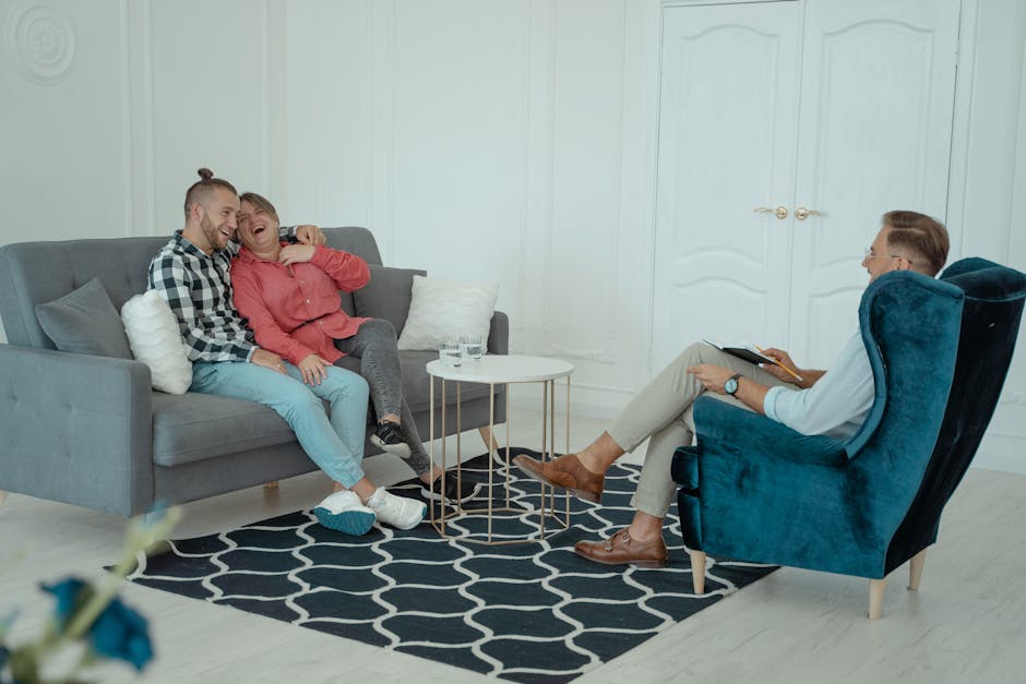 A happy couple enjoying a light moment in a therapy session with a therapist indoors.
