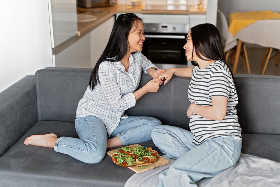 Cheerful couple sitting together on sofa with pizza, sharing a joyful moment indoors.