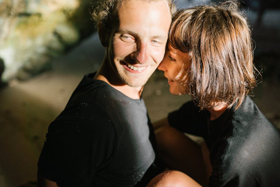 Playful and intimate moment of a couple sharing smiles and joy in a sunny outdoor setting.