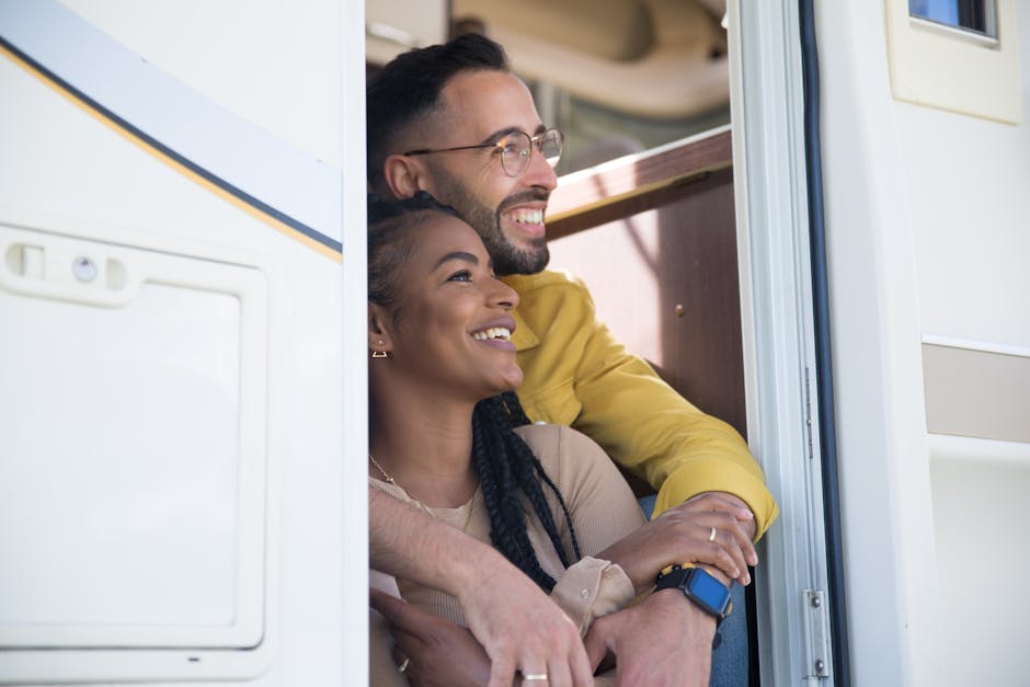 A joyful couple enjoys a moment together sitting in their RV doorway, exuding love and happiness.