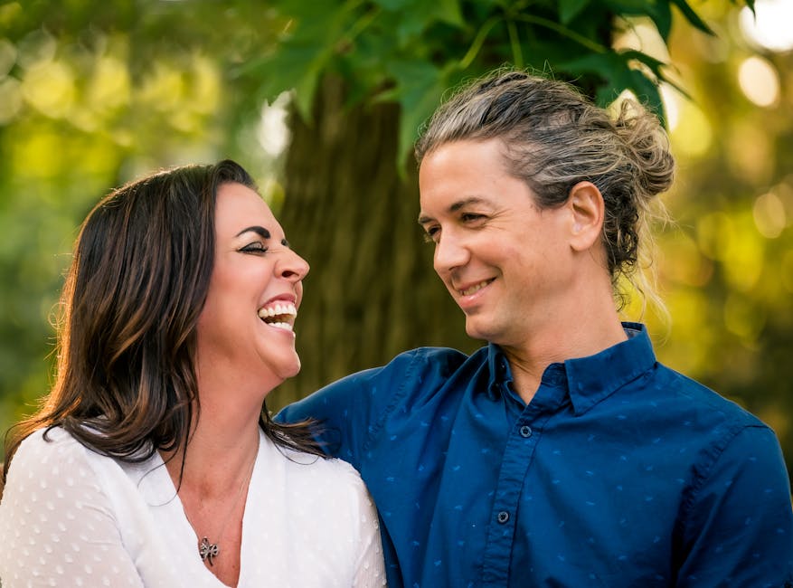 A happy couple laughing together outdoors, capturing a joyful moment in nature.
