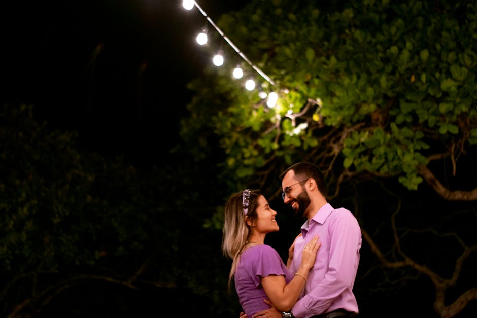 A happy couple in purple shirts enjoying a romantic moment under string lights in Brazil.