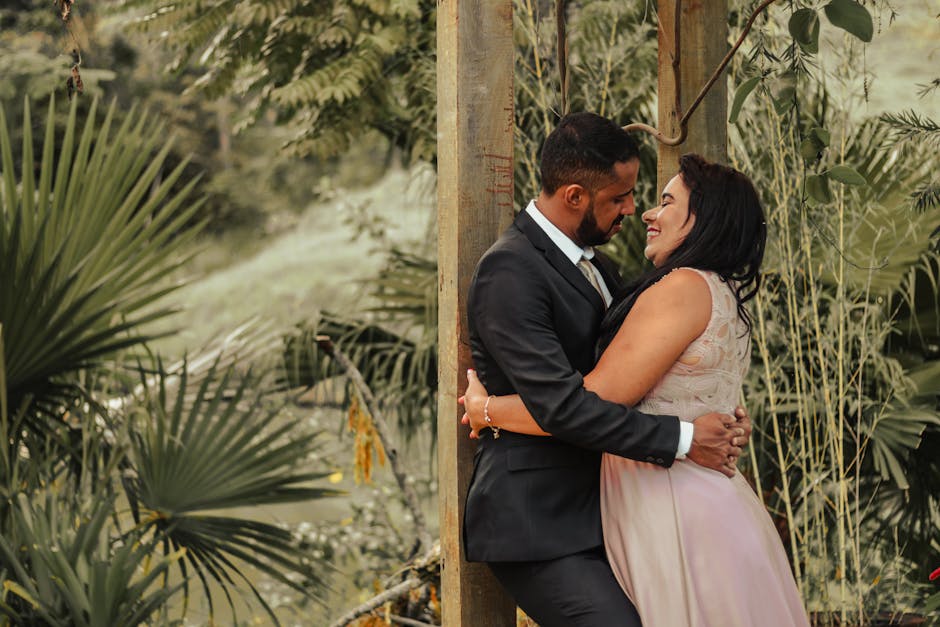 A loving couple embracing outdoors in a romantic, tropical setting, perfect for wedding photography.