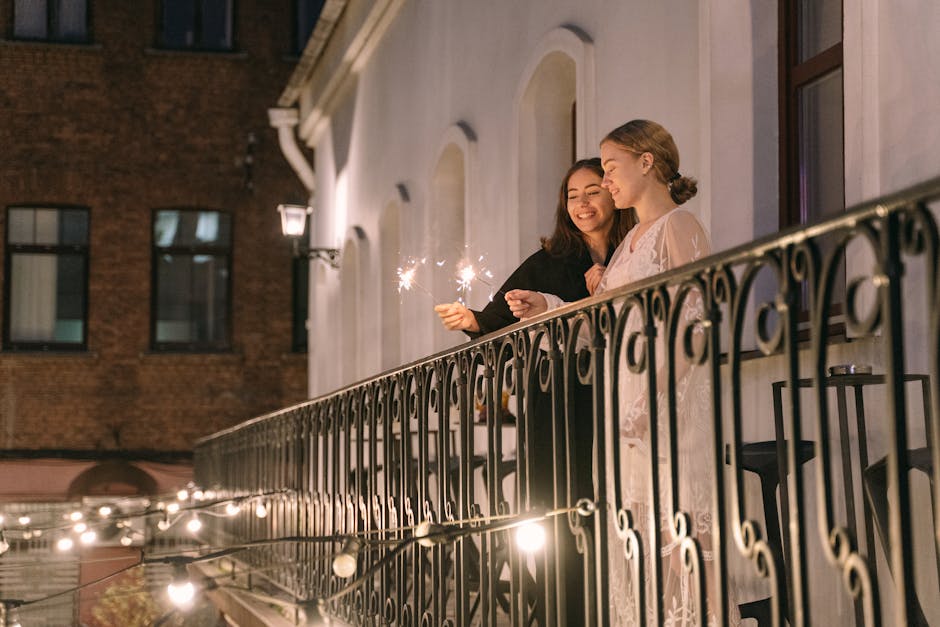 Two women enjoy sparklers on a balcony at night, creating a festive and intimate atmosphere.