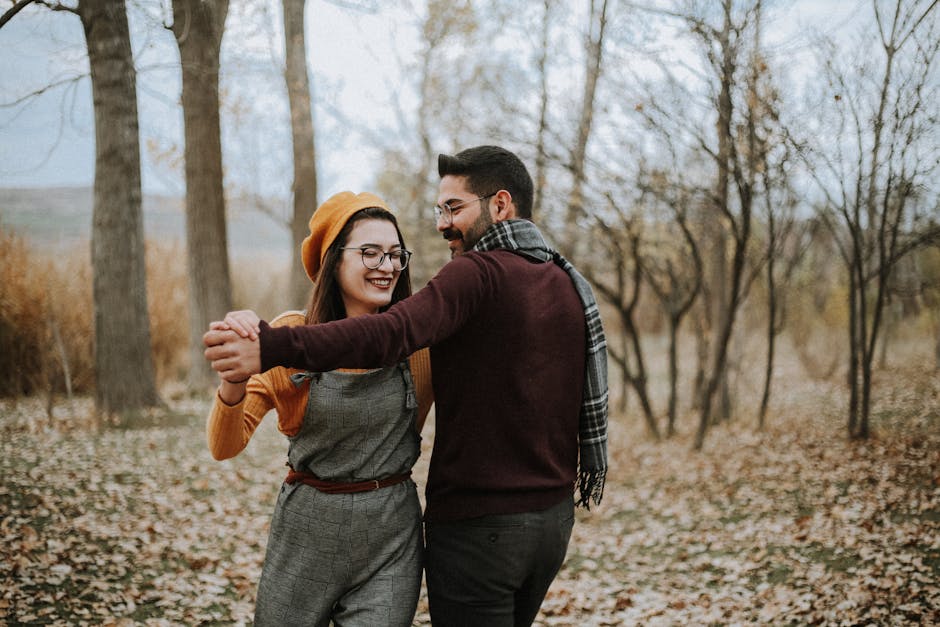 Happy couple enjoying a dance in a scenic autumn setting outdoors.