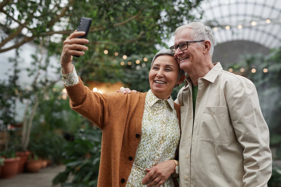 Happy senior couple taking a selfie in a lush garden setting, capturing a joyful moment.
