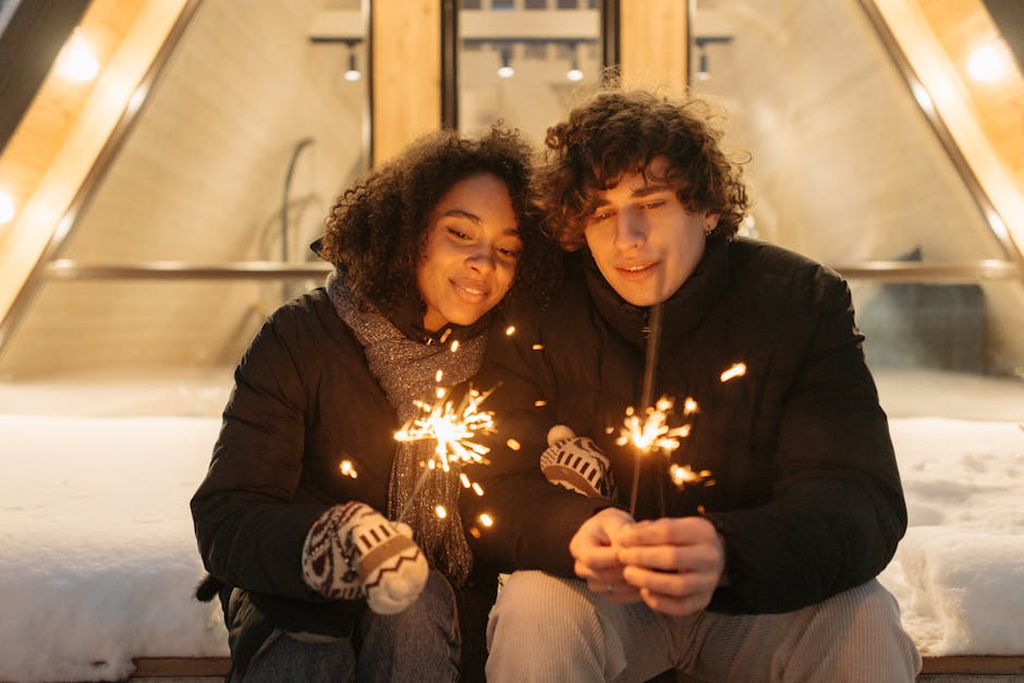 Cozy couple enjoying winter evening holding sparklers in a festive outdoor setting.