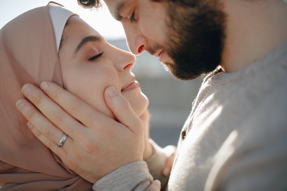 A couple shares an intimate moment outdoors, embracing tenderly.