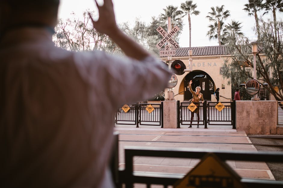 Two friends reunite at a train crossing, capturing a joyful moment in Pasadena.