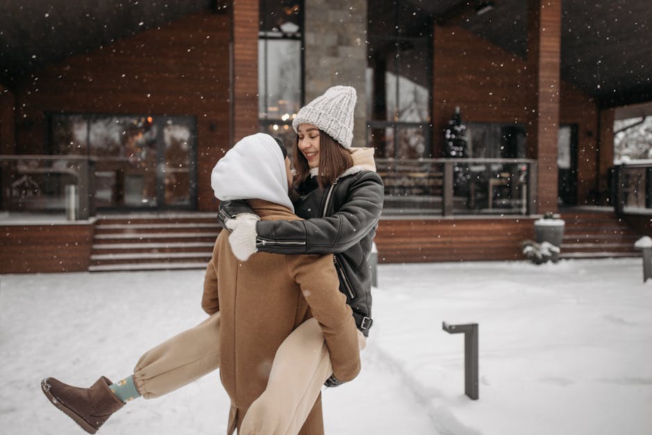 A young couple joyfully embraces during a snowy winter day, portraying warmth and romance.