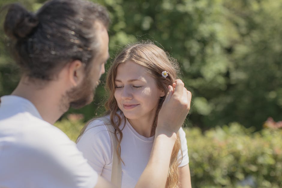 A smiling couple enjoying a sunny day outdoors with a flower in the woman's hair.