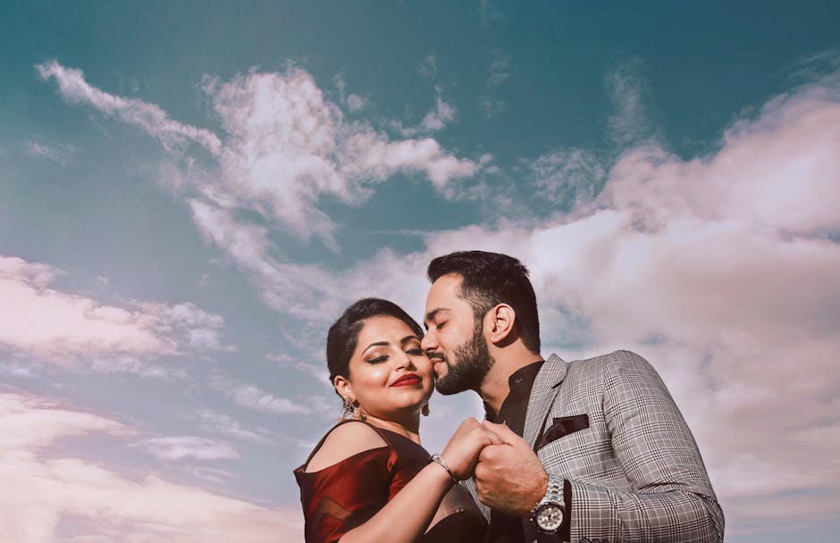 A loving couple holds hands and kisses under a vibrant sky, showing affection and romance.