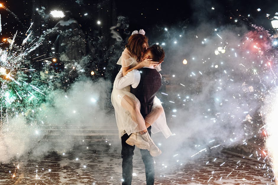 A loving couple shares a kiss surrounded by colorful fireworks during a festive night celebration.