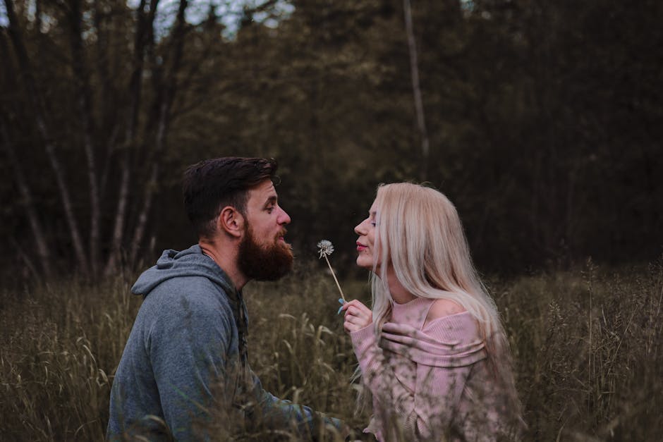 A loving couple facing each other in a serene forest clearing with a dandelion.