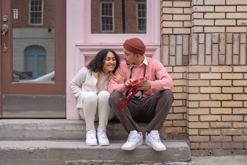 Young couple sitting outdoors sharing a romantic moment with a gift.
