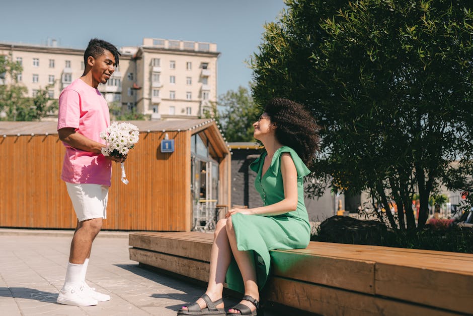 Man surprises woman with flowers in a romantic outdoor setting.