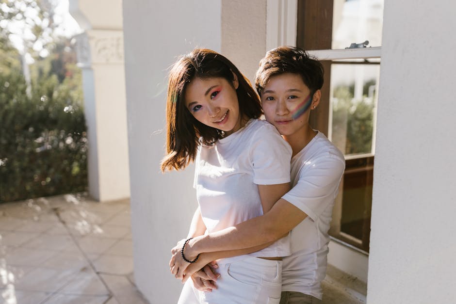 A loving LGBTQ+ couple embracing, adorned with colorful face paint, celebrating pride outdoors.