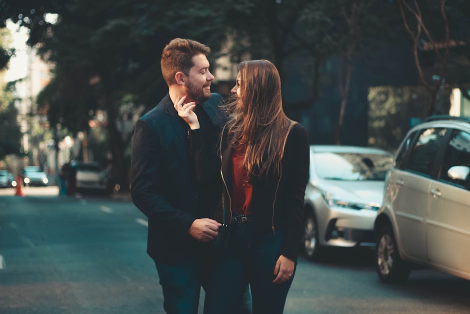 A romantic couple happily walking on a city street in daylight, enjoying each other's company.