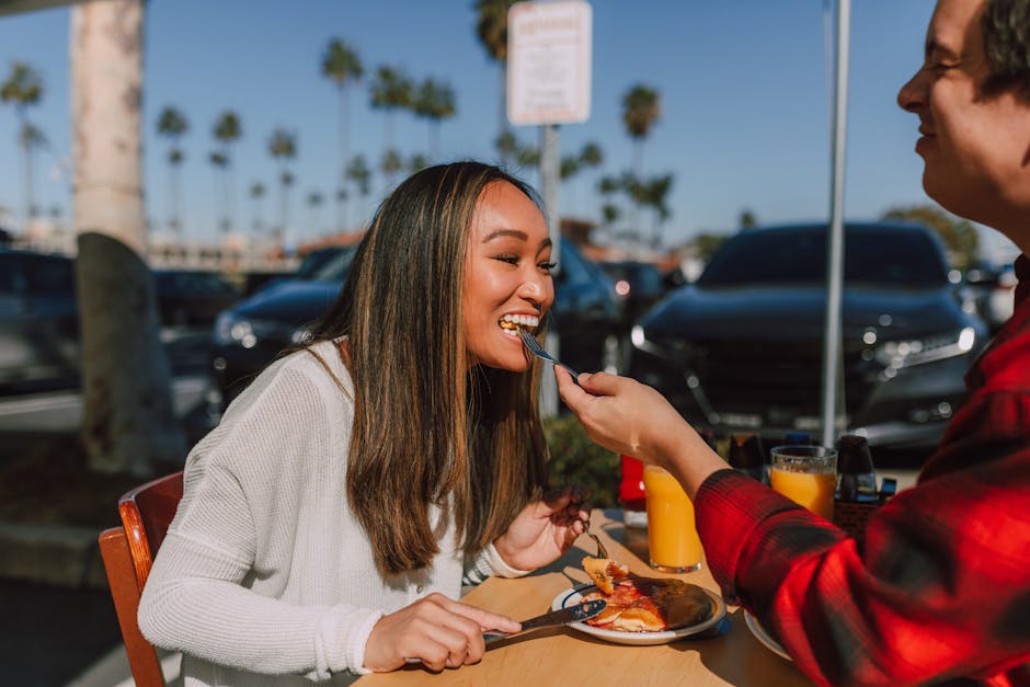 A couple enjoying a sunny brunch outdoors, sharing pancakes and juice, creating a sweet and joyful moment.